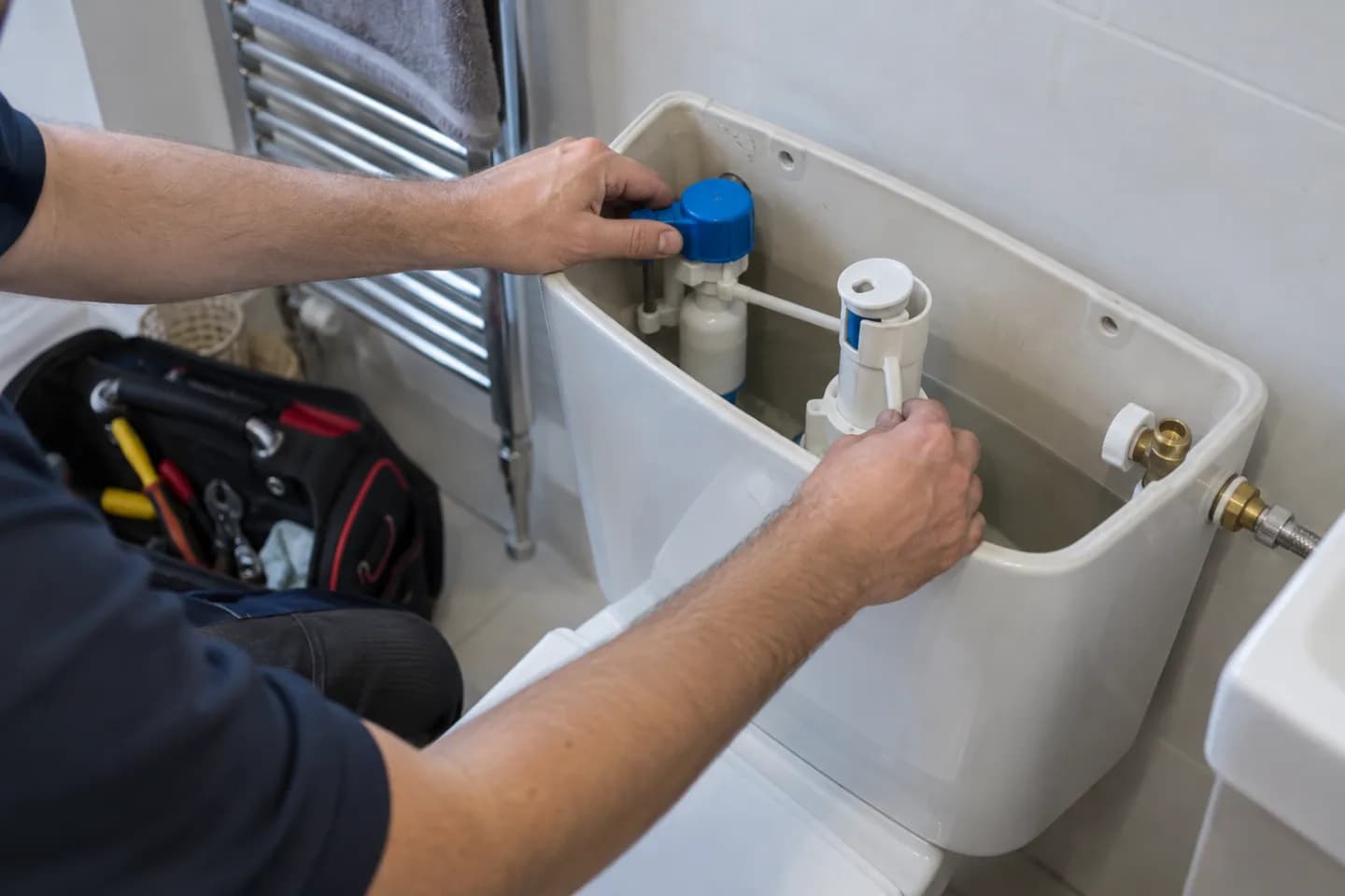 Plumber inspecting the mechanism inside a toilet cistern
